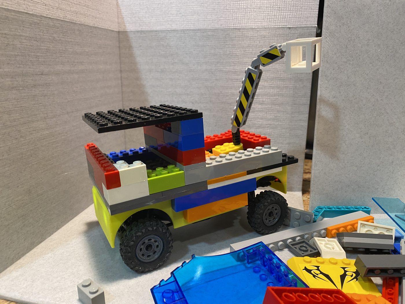 A vehicle built from plastic building bricks on the enclosed platform, with a crane arm on the back.