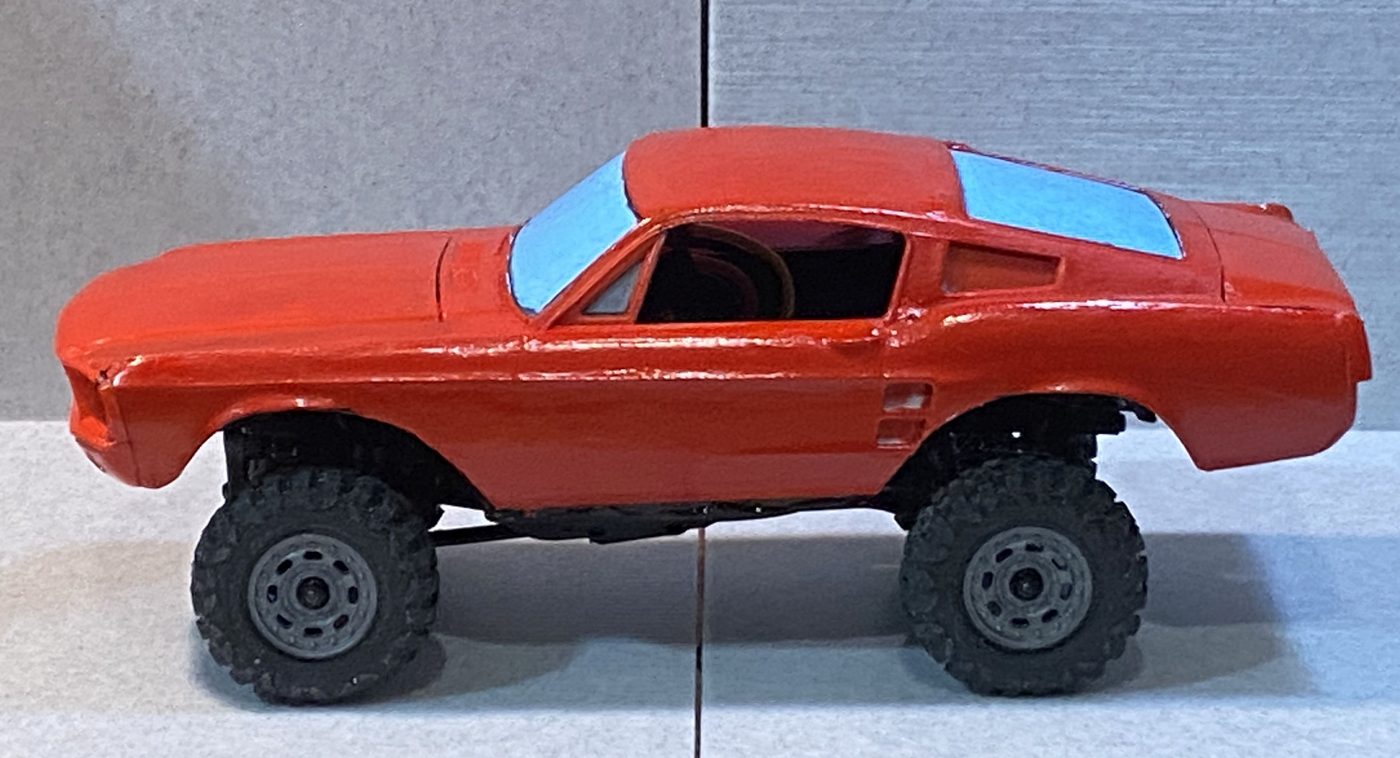 A red Mustang body, painted and finished, mounted high on the chassis with the arches out of line with the wheels.